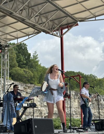 A singer and band performing on the main stage in the afternoon sun