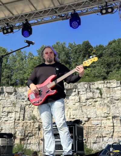A bass player performing in front of the quarry wall