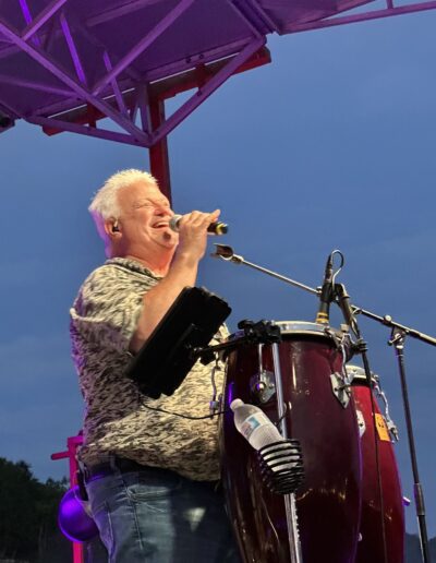 A singer performing beside conga drums at night