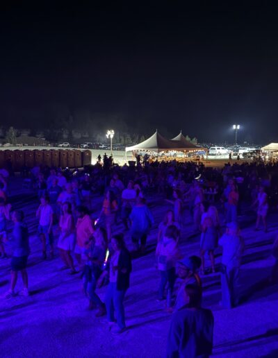 The crowd dancing with glow sticks in front of the stage at night