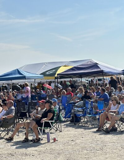 A packed crowd in lawn chairs under the tents watching the show