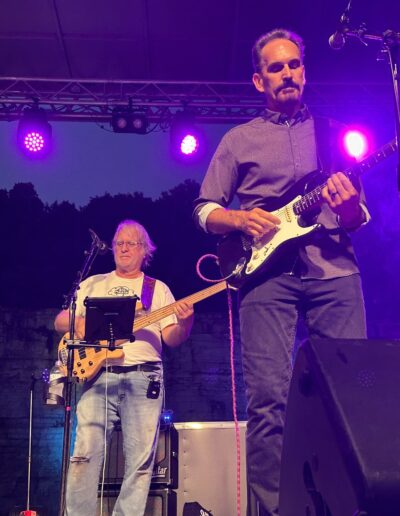 A guitarist and bass player performing together at night