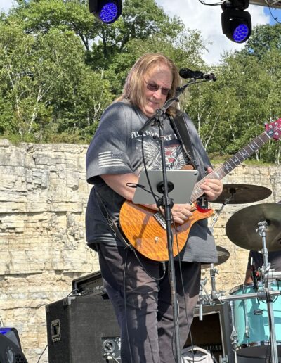 A guitarist playing on the main stage with the quarry wall behind