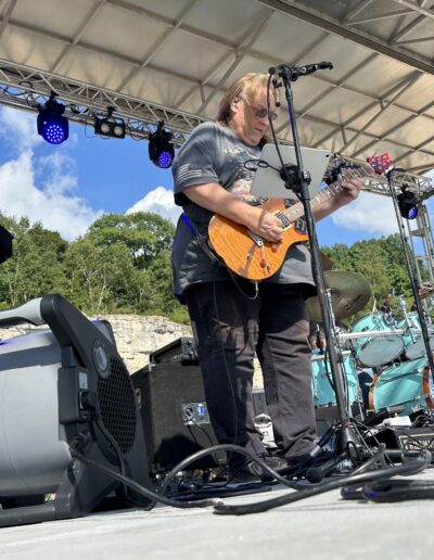 A guitarist performing on the main stage under the stage lights