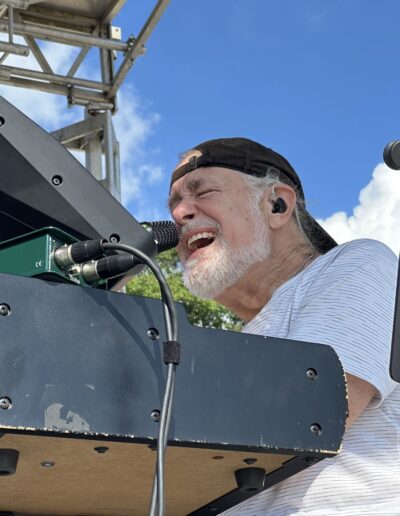 A keyboard player singing on the main stage in the afternoon