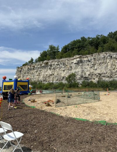Bounce houses and a sand play area at the base of the quarry wall