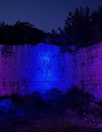 The Old Stone Quarry wall lit in purple and blue after dark