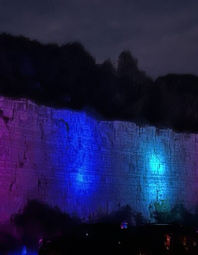 The quarry wall glowing pink and blue during the light show