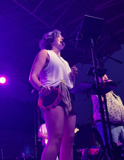 A vocalist performing under purple stage lights at night